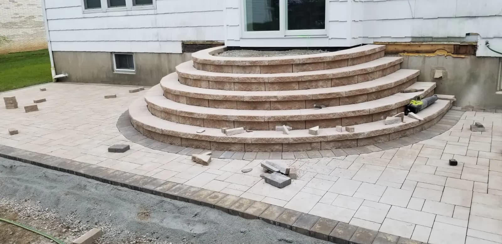 Wide curved masonry entrance steps meeting a gray paver landing